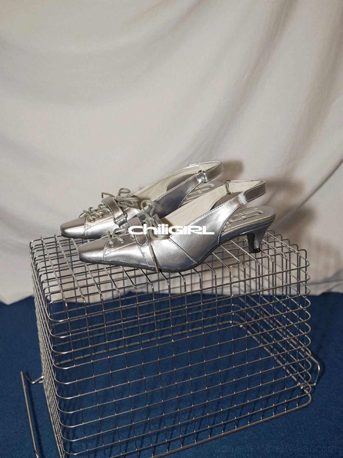Silver slingback kitten heel shoes displayed on a metal rack showing the side profile and low heel