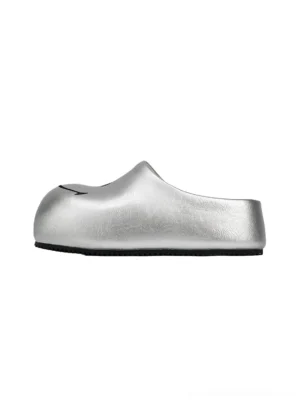 Silver smiley face chunky slip-on mule sandals shown from the left side, featuring a metallic textured upper, rounded closed toe, and bold black sole on a white background