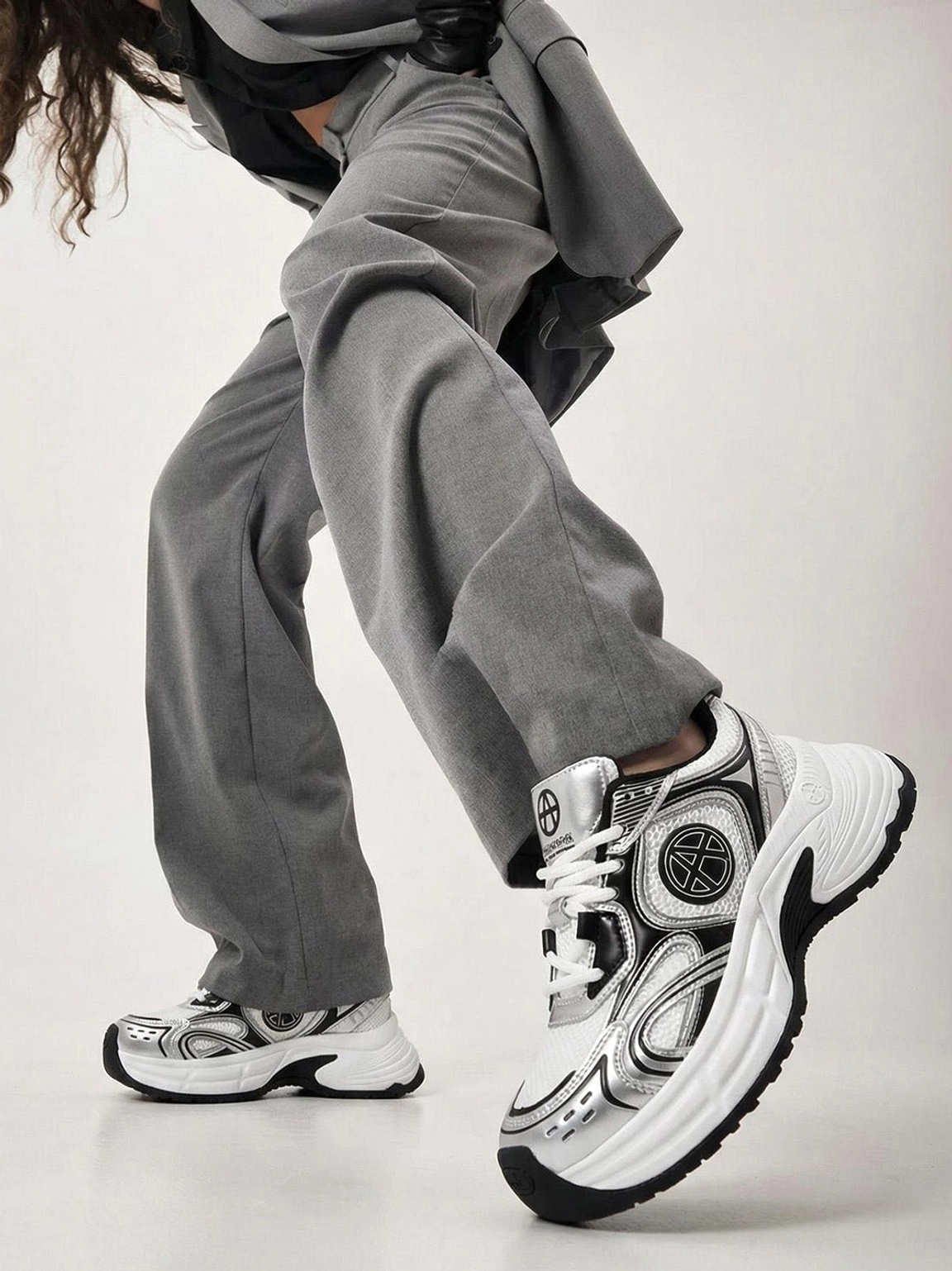 Silver Wave chunky dad sneakers styled with grey wide-leg pants in a low-angle Korean streetwear outfit showing the thick runner sole
