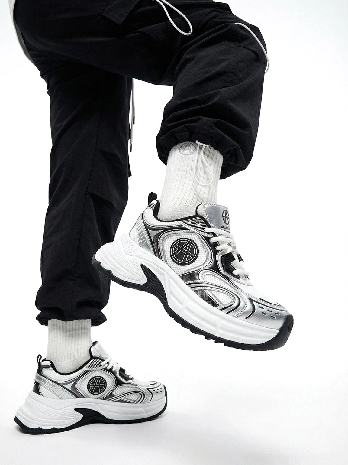 Silver Wave chunky dad sneakers shown from a low angle with black cargo pants and white socks highlighting the chunky rubber outsole