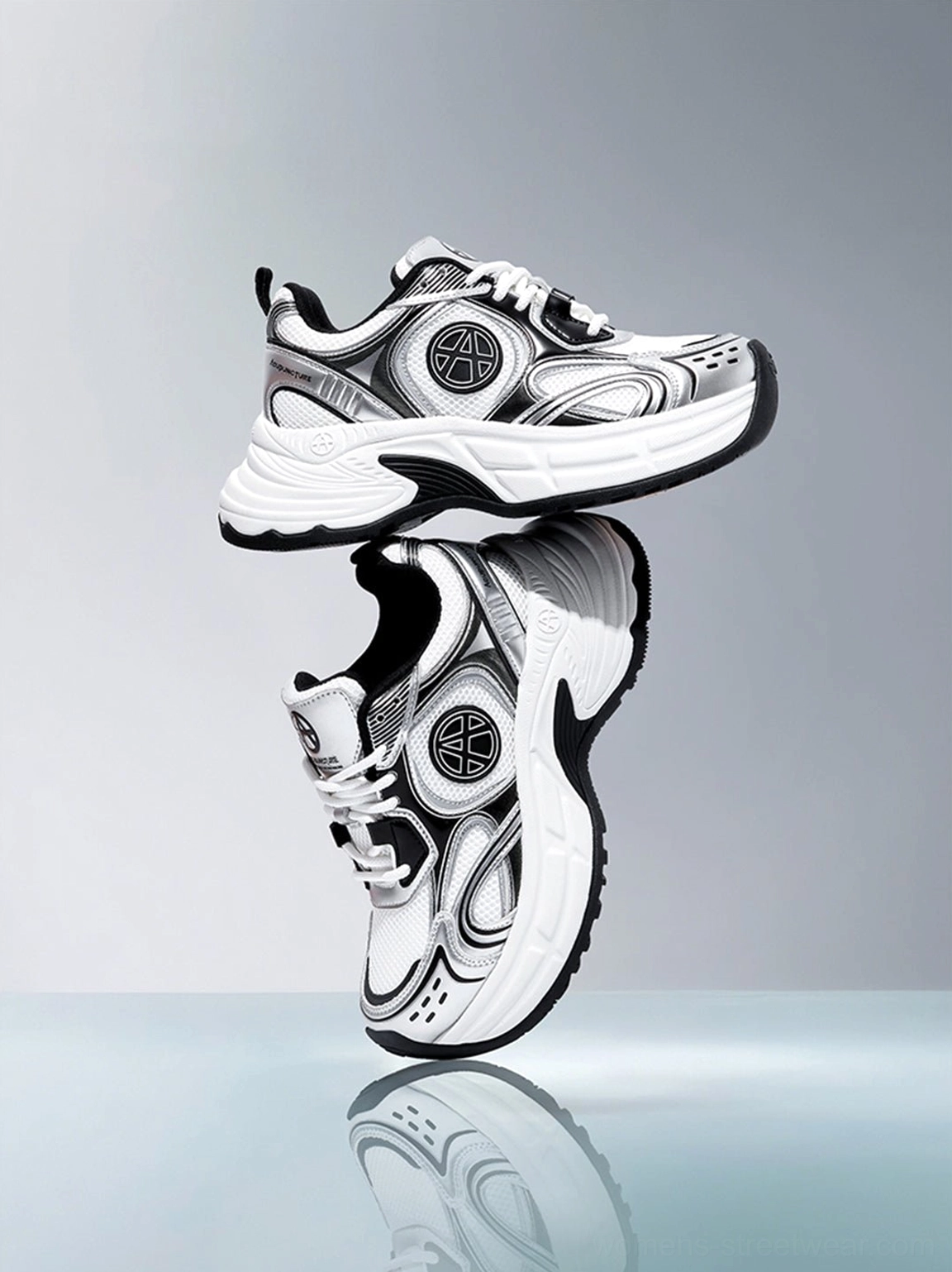 Silver Wave chunky dad sneakers stacked on a reflective studio surface displaying the shiny metallic silver upper and layered design