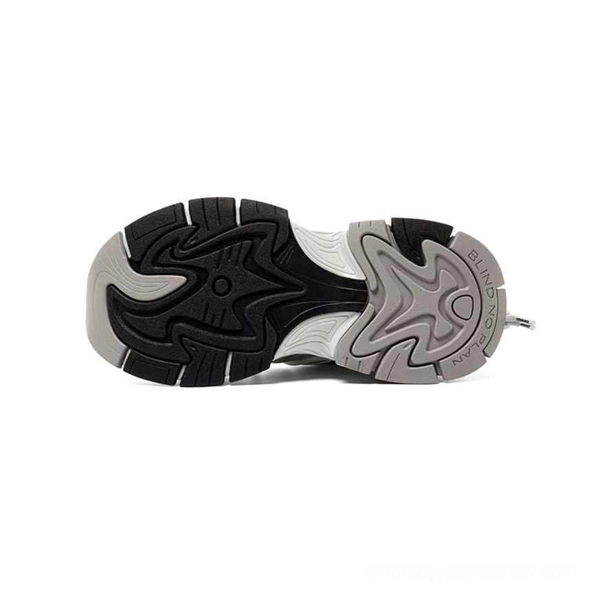 Bottom view of silver white streetwear chunky runner sneaker showing multi-directional lug traction tread, two-tone black and grey outsole, and heel lettering detail