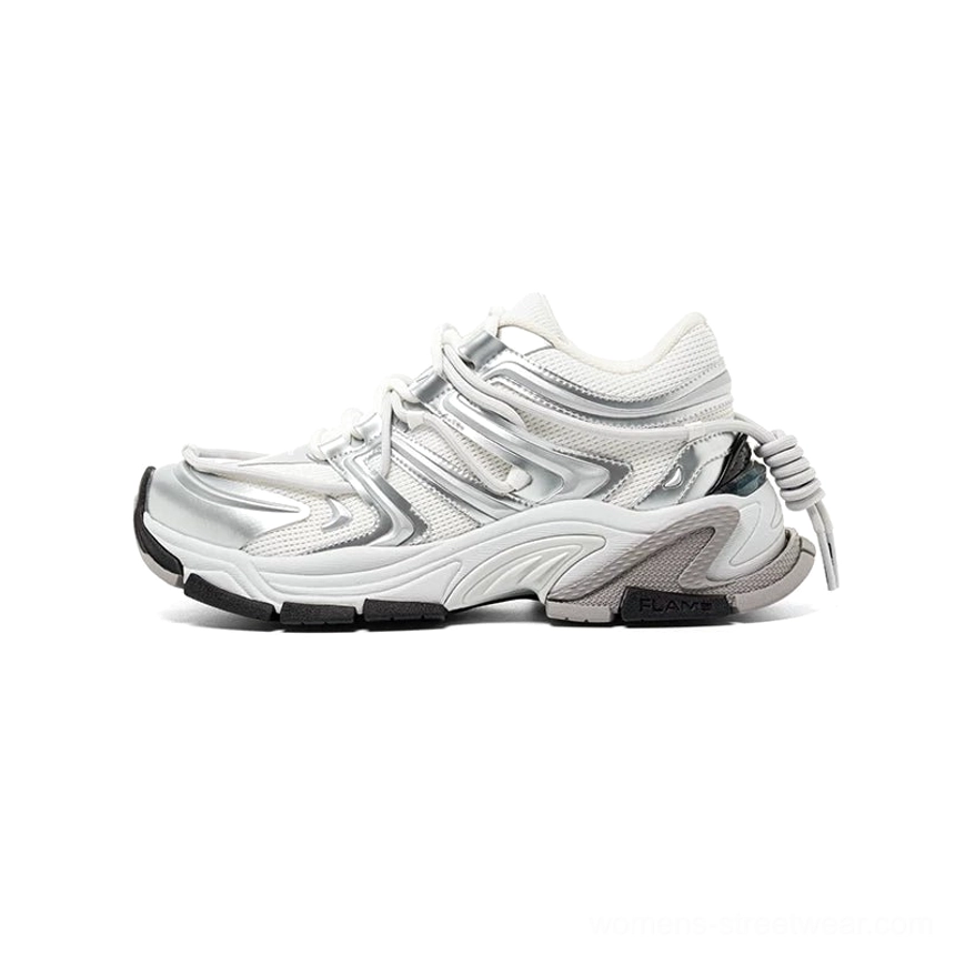 Lateral side view of a silver white chunky runner sneaker with layered metallic overlays, white mesh panels, sculpted midsole, thick rubber outsole, and heel drawstring accent