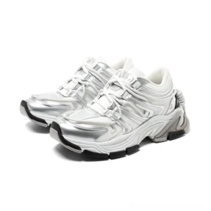 Silver white chunky runner sneakers shown in three-quarter side view with layered metallic sculpted panels, thick rubber sole, lace-up front, padded low-top collar, and heel drawstring detail