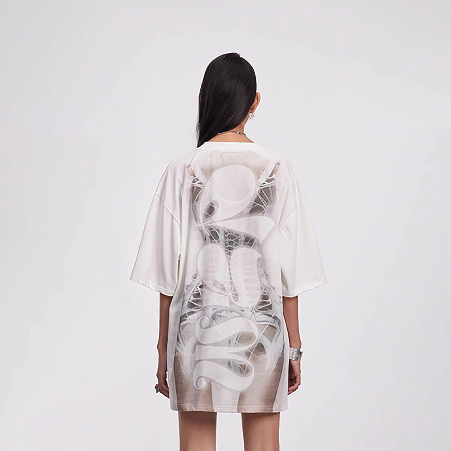 Back view of an off-white oversized skeleton streetwear tee dress showing spine artwork and relaxed loose silhouette