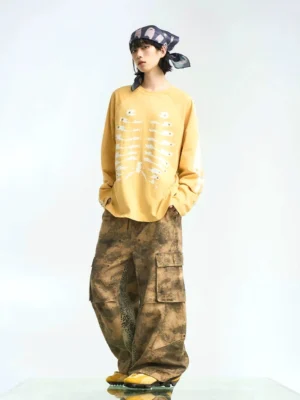 Mustard yellow skeleton print raglan long sleeve streetwear t-shirt styled with tie-dye cargo pants in a full-body studio outfit