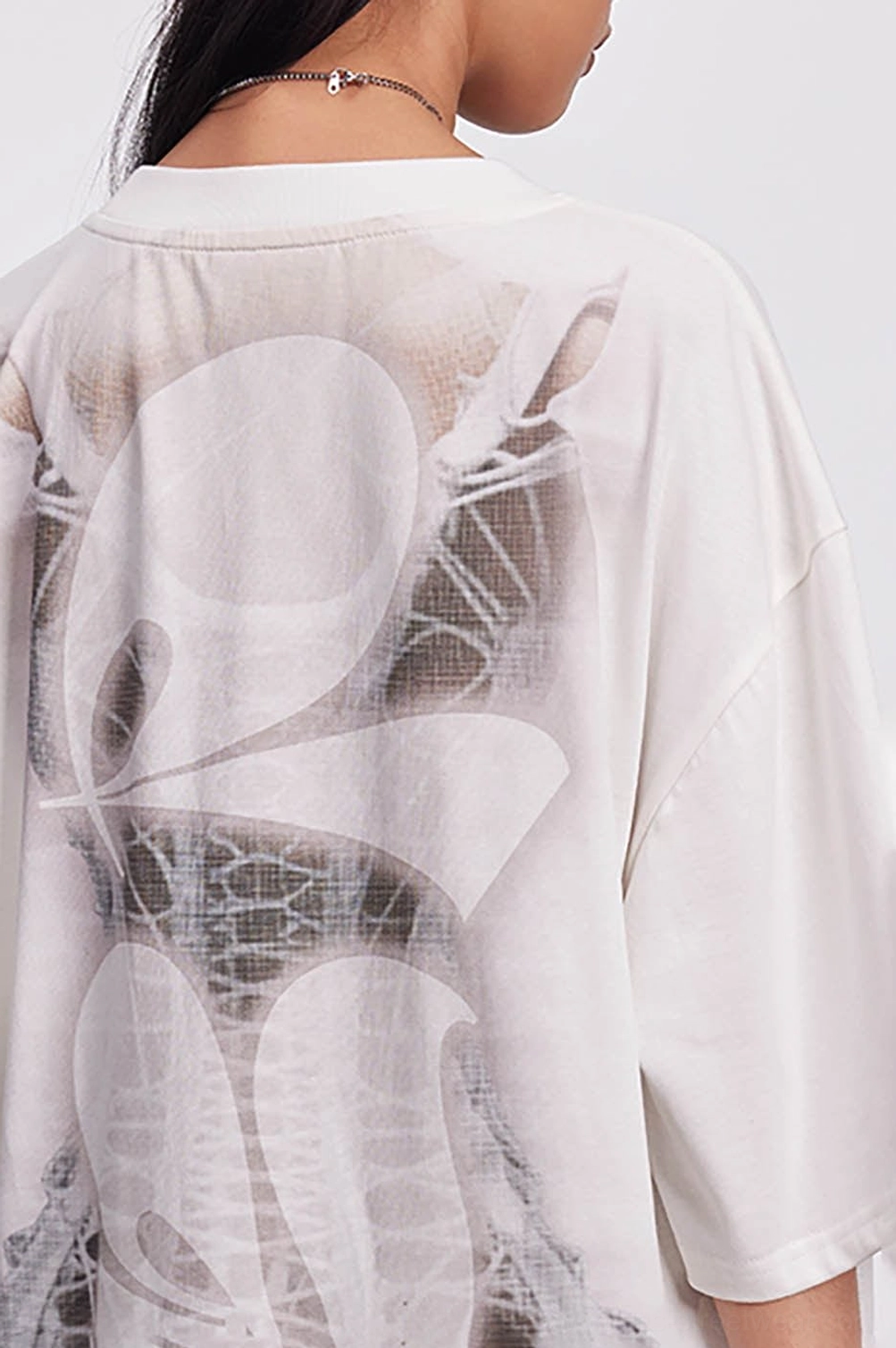 Upper back detail of an oversized skeleton streetwear tee with large graphic print, crew neckline, and loose sleeves