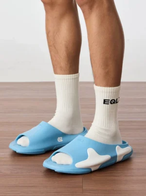 Model wearing sky blue and white cloud cushion open-toe slides with white crew socks on an indoor wood floor