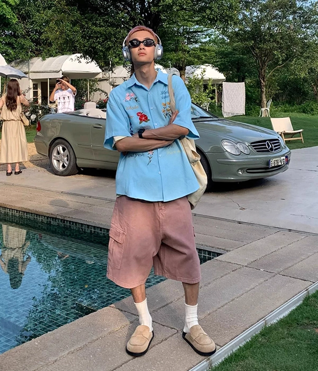 Sky blue floral embroidered short sleeve button-up shirt styled beside a pool in a casual summer streetwear outfit