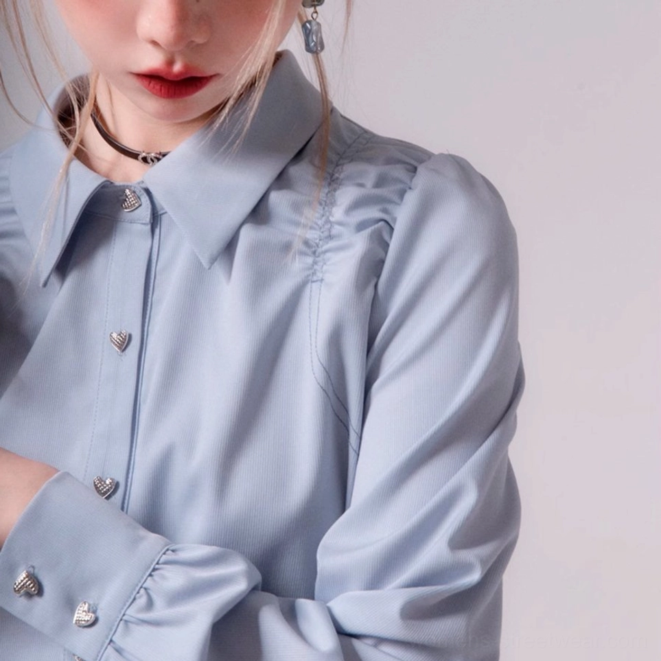 Close-up detail of heart-shaped buttons pointed collar ruched shoulder seam and cuff on sky blue blouse