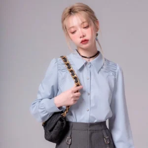 Sky blue heart button ruched shoulder blouse styled with a dark gray high-waisted skirt and chain bag