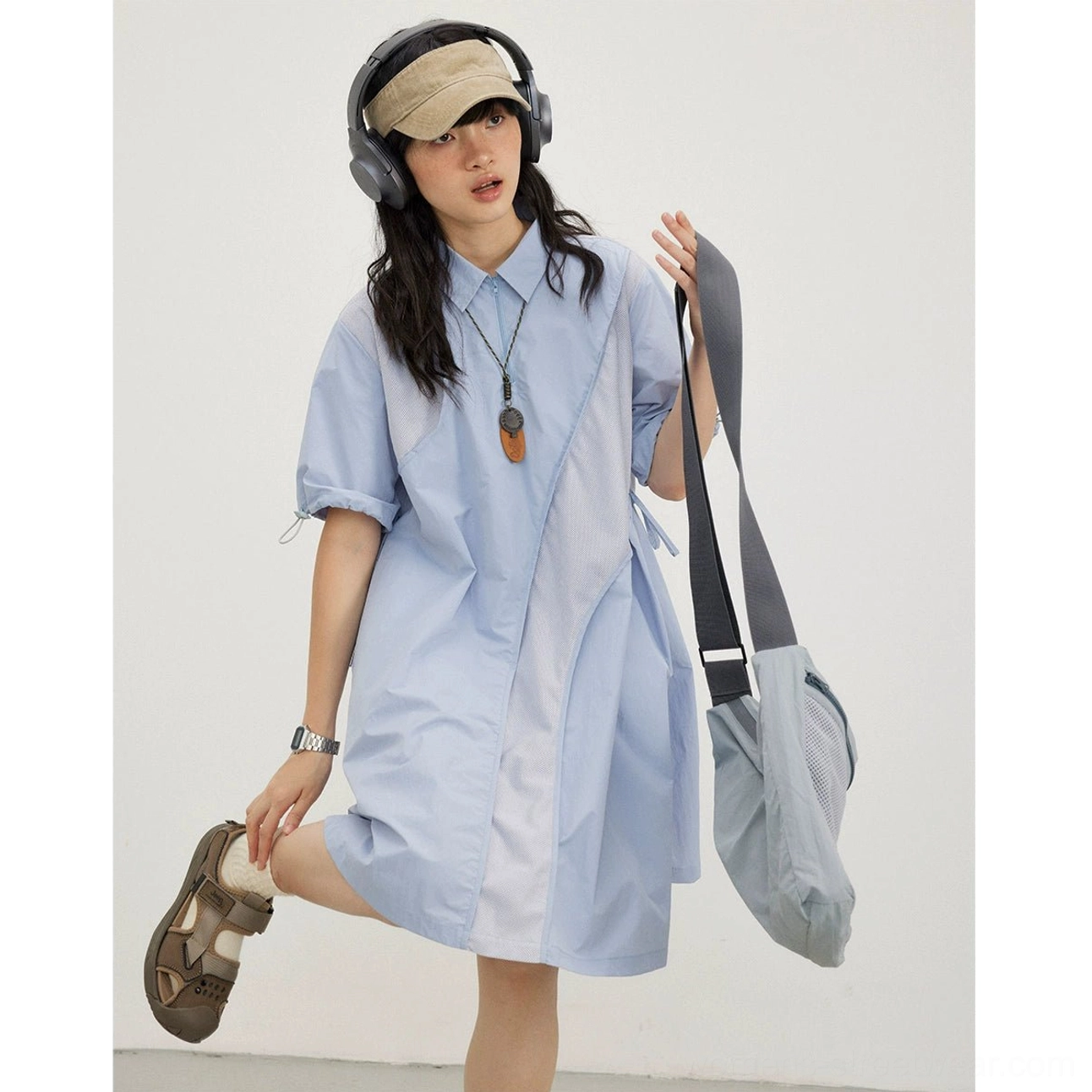 Sky blue oversized mesh shirt dress in a dynamic streetwear pose with gray tote bag and headphones