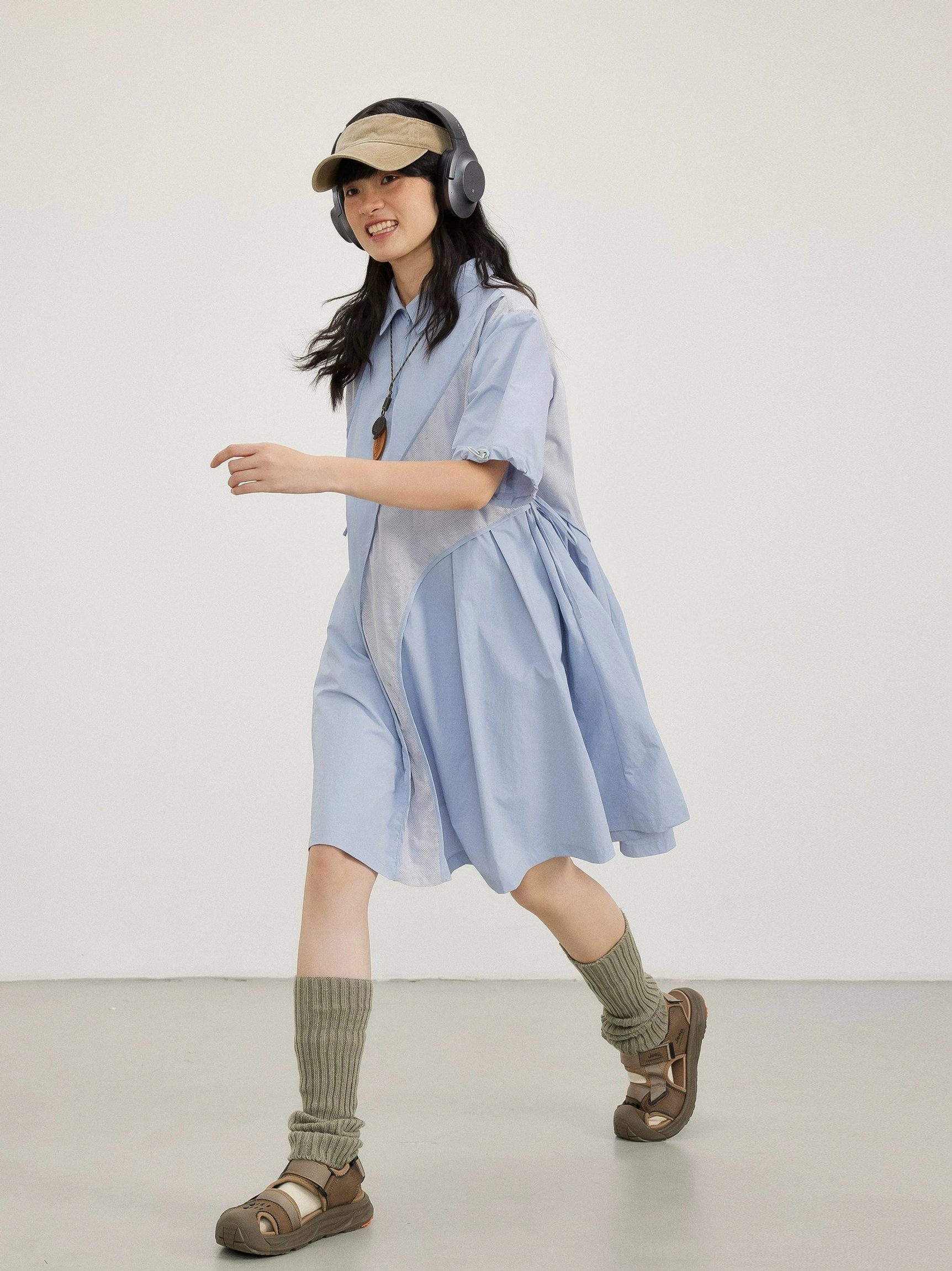 Sky blue oversized technical mesh shirt dress with short puff sleeves and pleated hem styled with a baseball cap and headphones