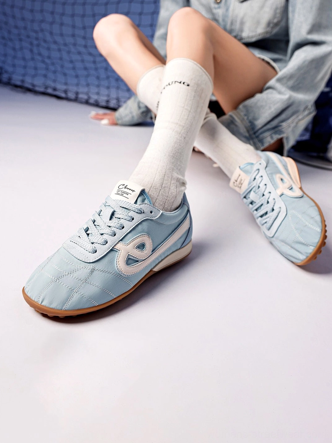 Seated woman styling sky blue quilted gum sole retro streetwear sneakers with denim outfit