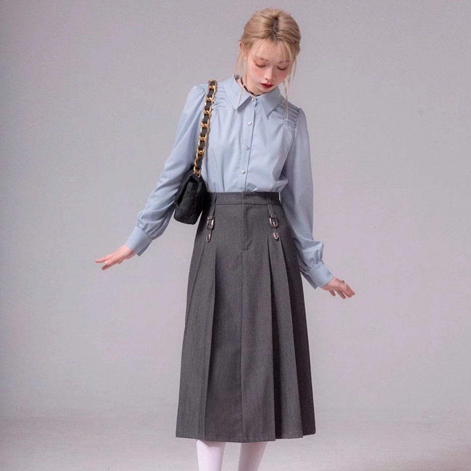 Full side outfit view of sky blue ruched shoulder blouse with pleated midi skirt and shoulder bag