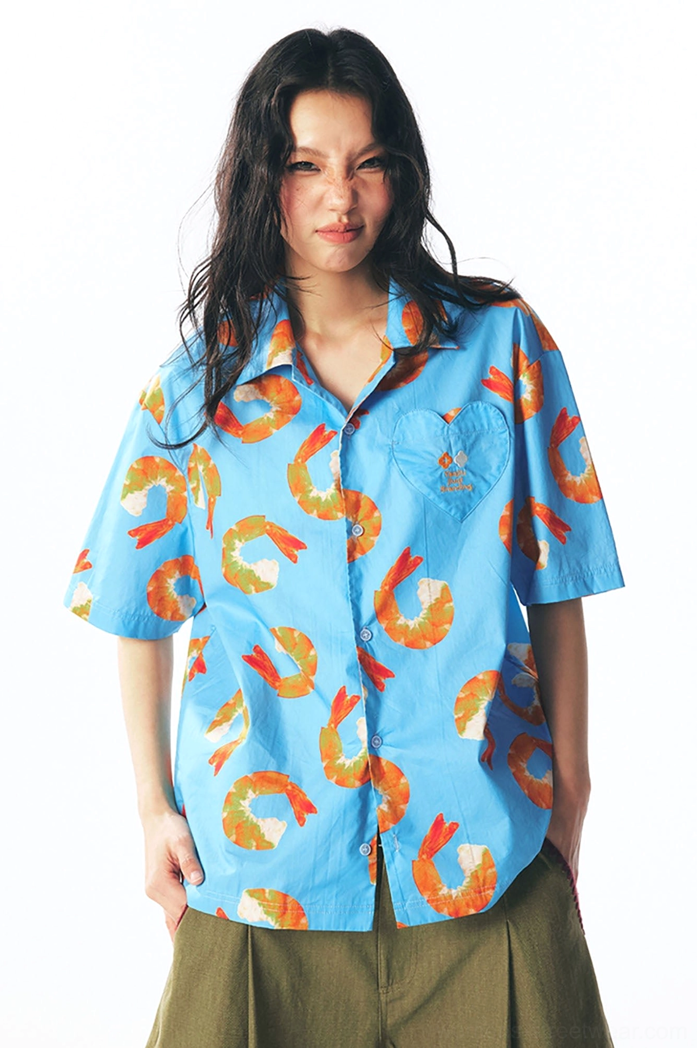 Front full-body view of fully buttoned sky blue shrimp print shirt styled with olive cropped trousers