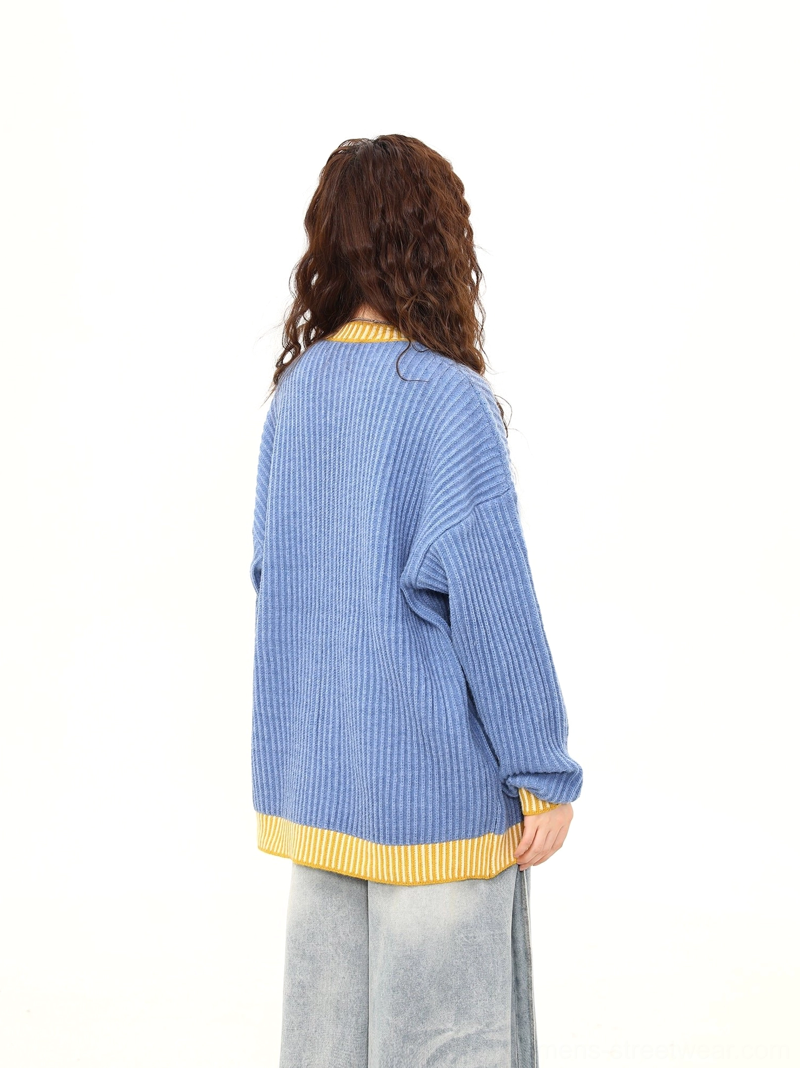 Full back view of oversized sky blue and yellow contrast ribbed cardigan worn with wide leg denim