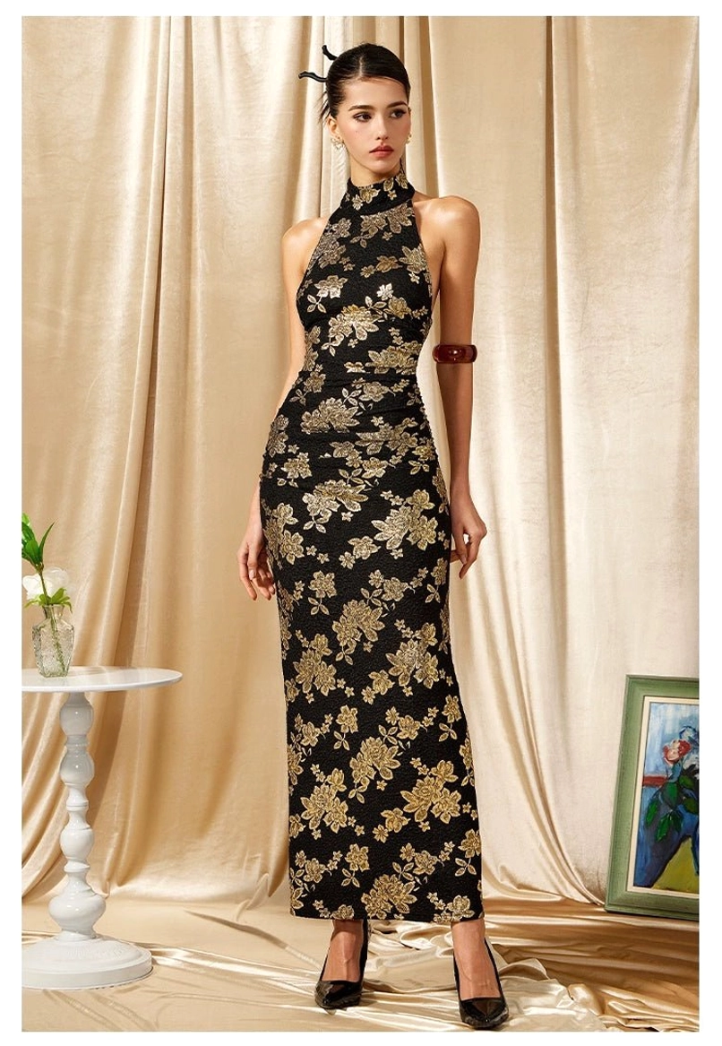 Front three quarter view of a sleeveless black cheongsam maxi dress with ornate gold floral pattern and high halter neck