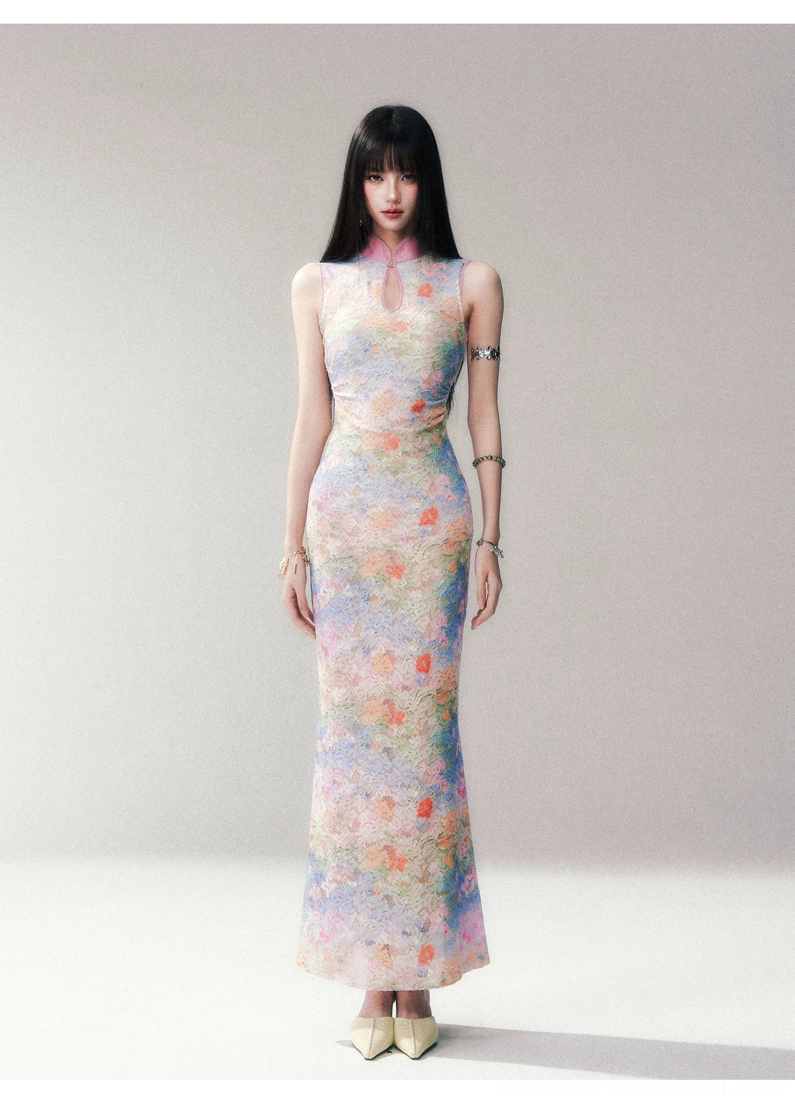 Full front studio view of a sleeveless bodycon watercolor floral qipao maxi dress with stand collar, keyhole neckline, all over pastel flower print, and matching metal bracelets