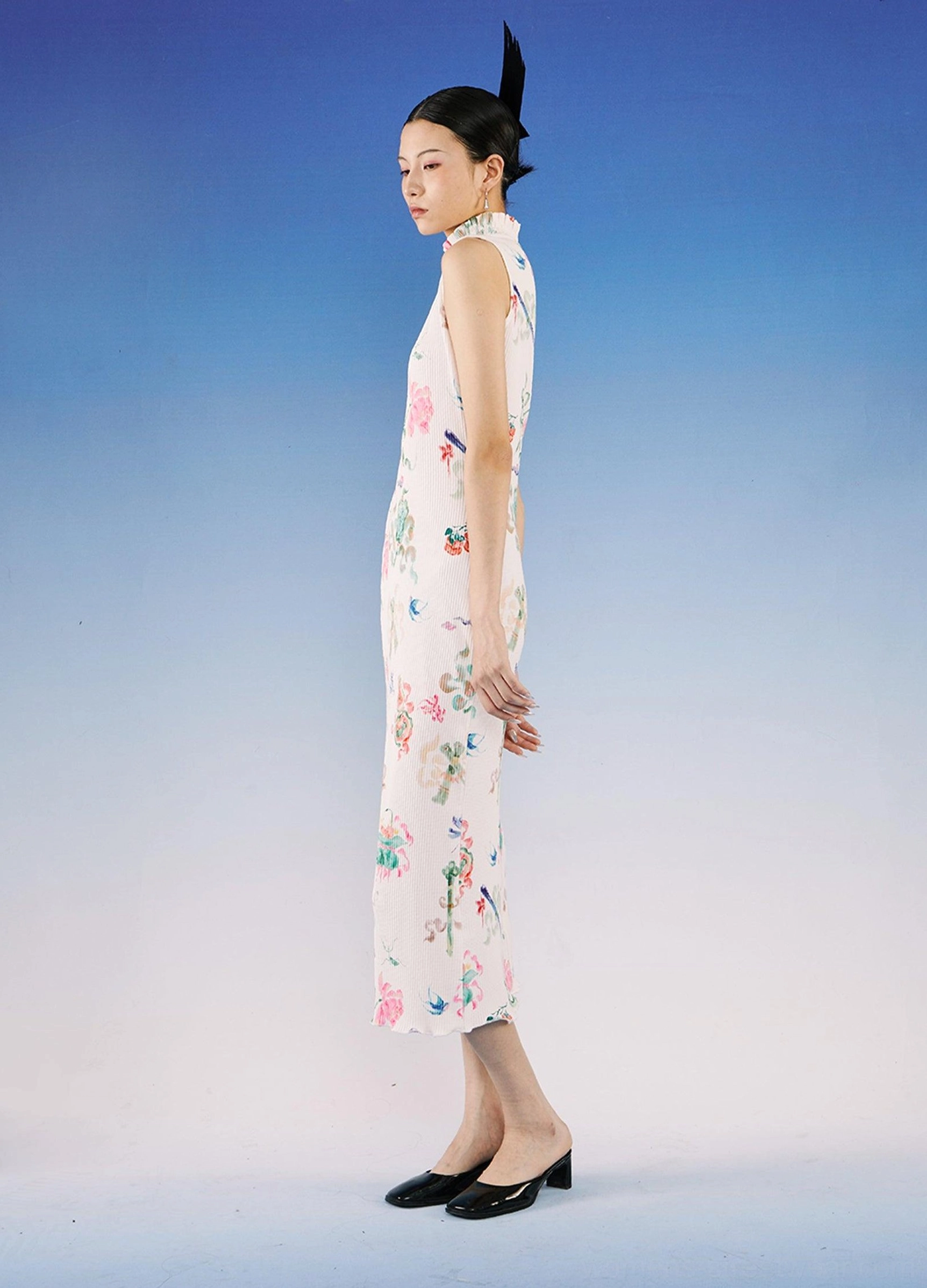 Side profile of a sleeveless watercolor floral qipao dress featuring a tailored midi silhouette, stand collar, and ribbed white textile