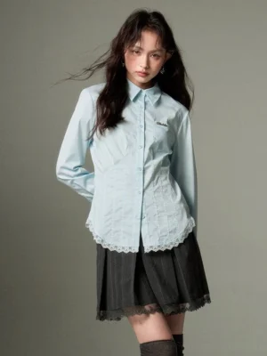 Pastel blue slim-fit lace-hem button-up shirt styled with a dark pleated skirt, over-the-knee socks, and leather shoes