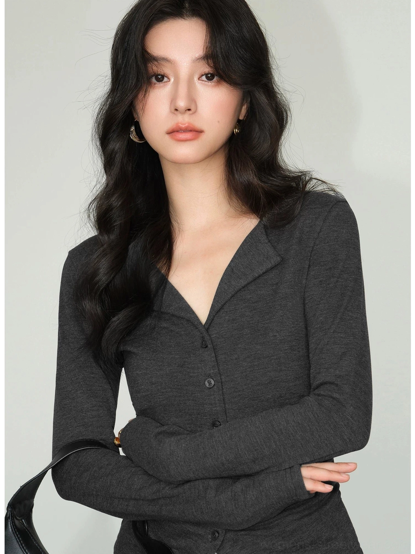 Dark gray slim fit button-front knit cardigan top with notched lapel collar and long sleeves styled with a black leather handbag