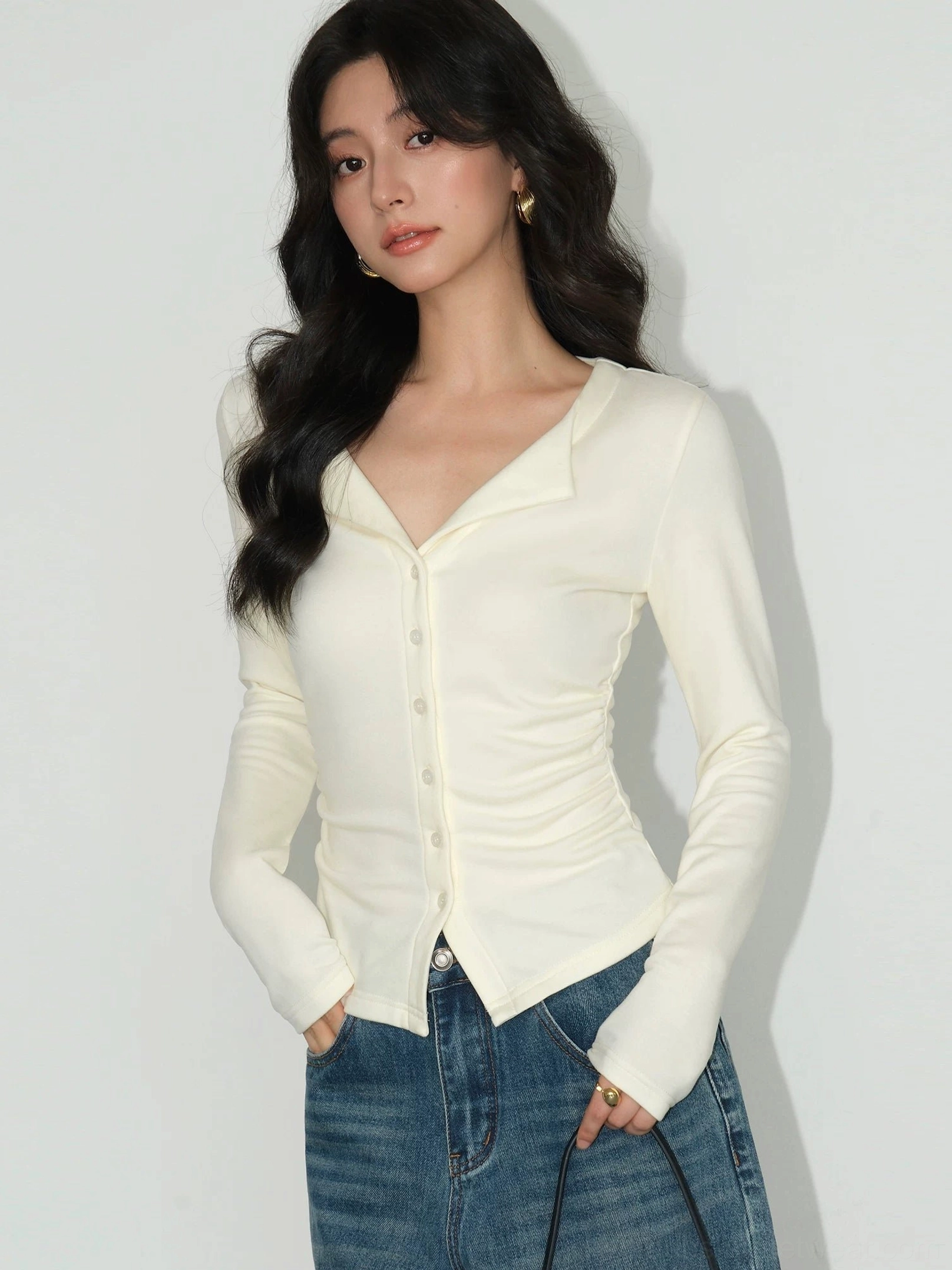Light apricot slim fit knit cardigan top with ruched side details curved hem and notched V-neck lapel styled with high-waisted blue jeans