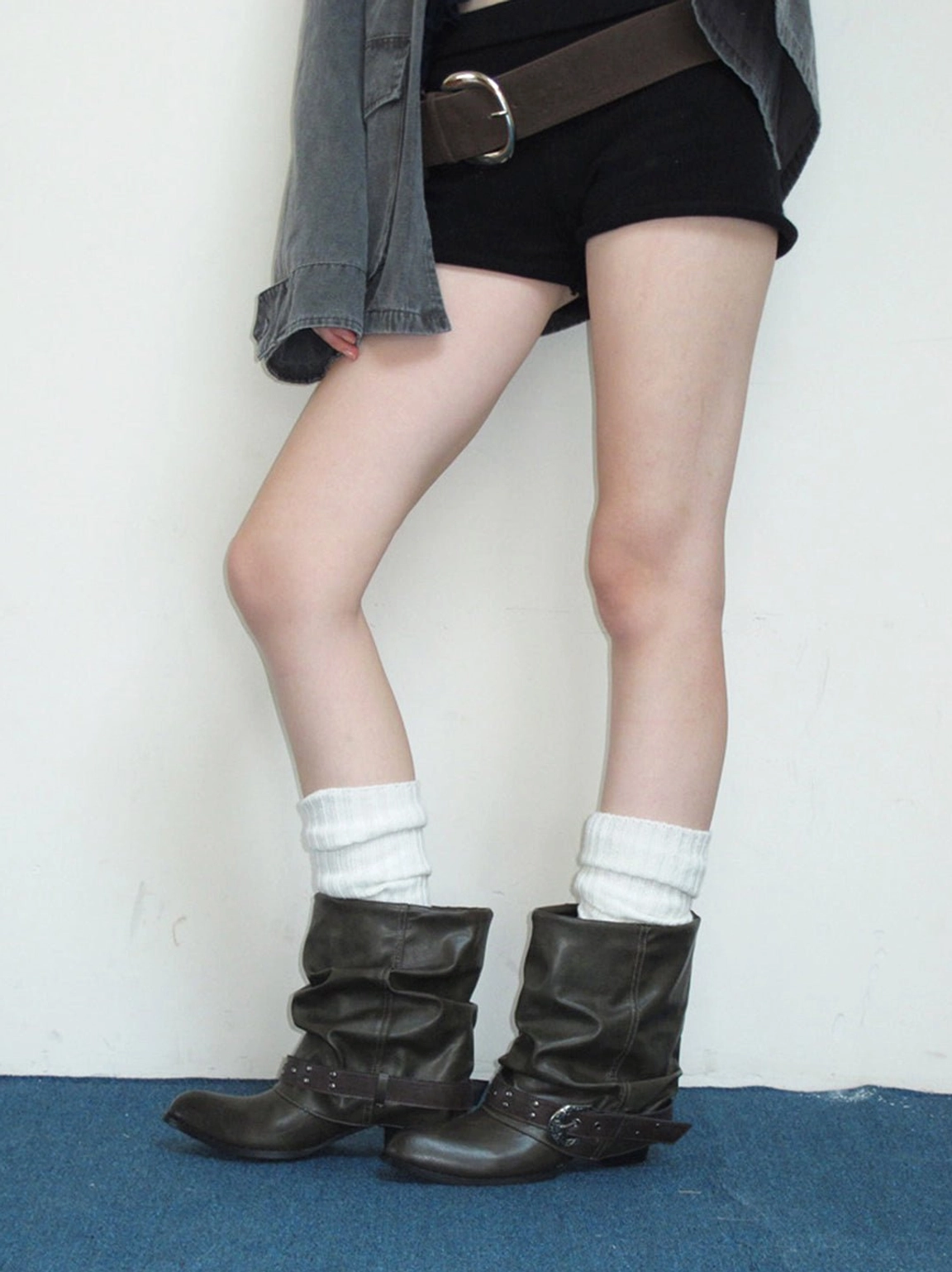 Slouchy brown western buckle ankle boots styled with cropped denim, black shorts, and a wide belt