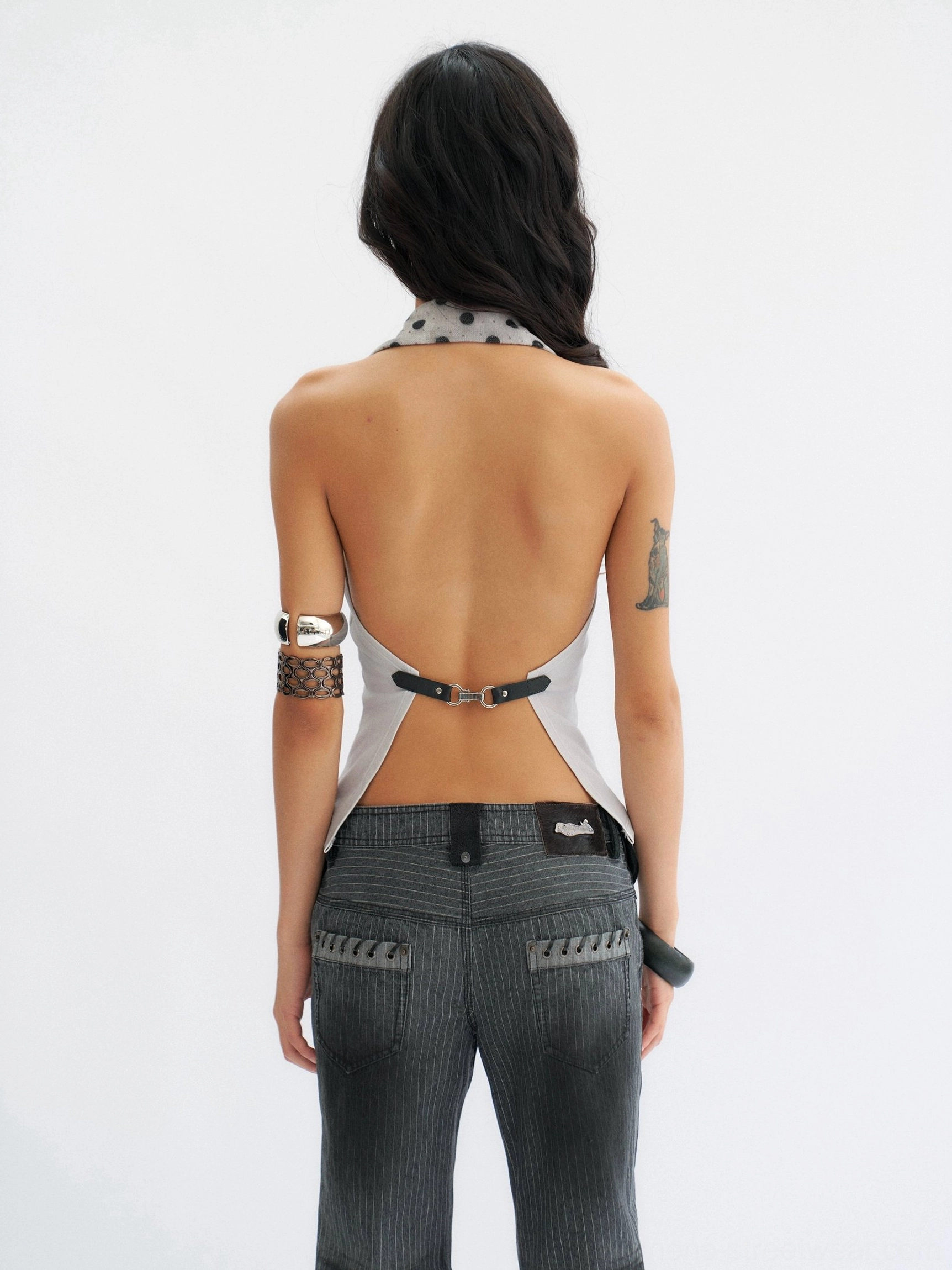 Close rear view of a smoke blue-gray backless cropped halter top highlighting the buckle closure, fitted bodice, and polka dot collar