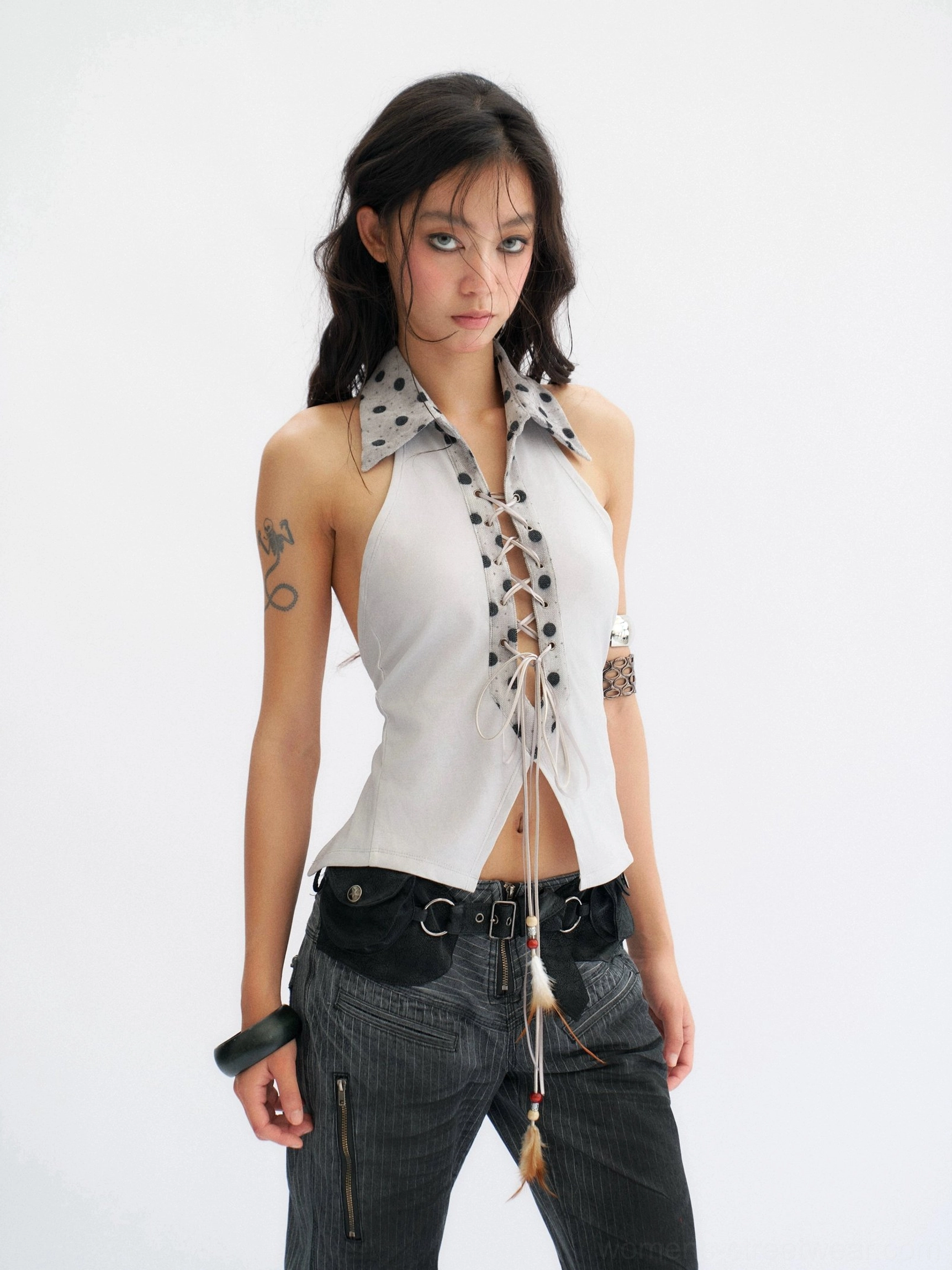 Close front view of a fitted smoke blue-gray backless halter top with adjustable lace-up bust detail and decorative tassel pendant