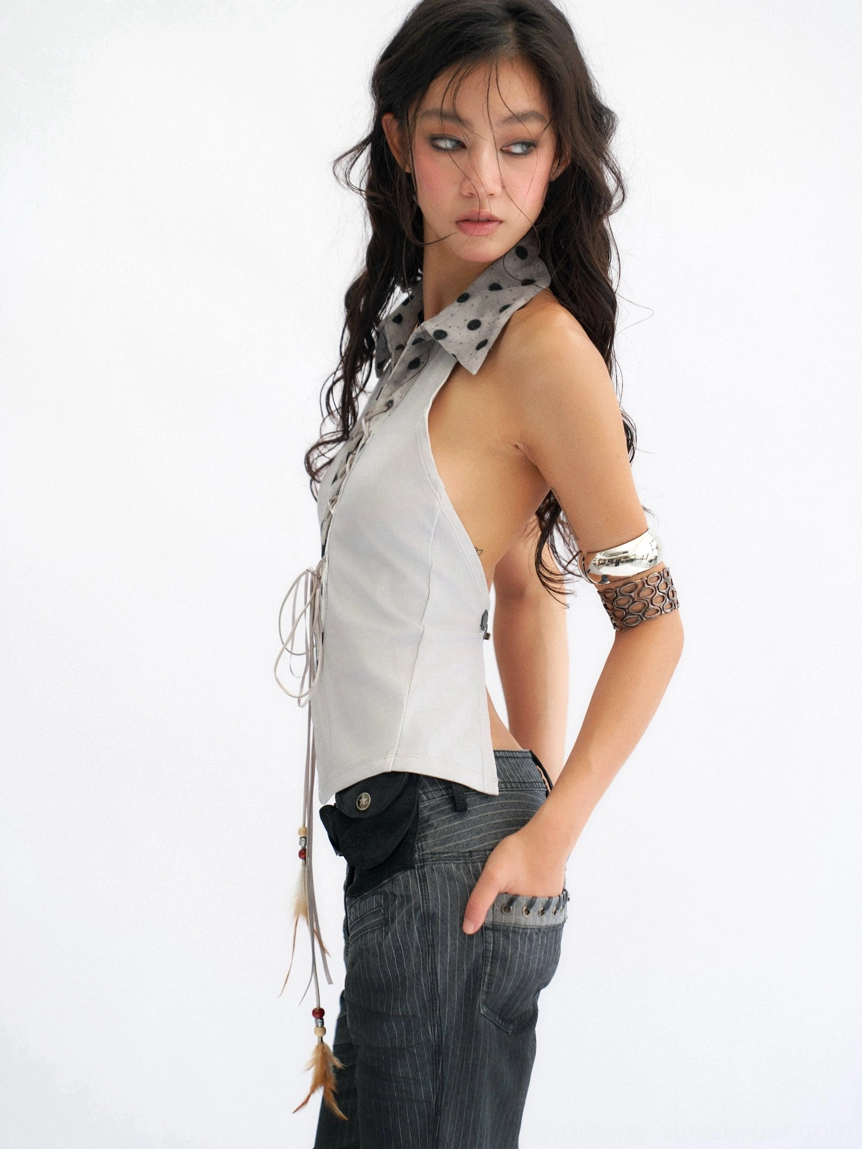 Left front view of a smoke blue-gray lace-up halter top with polka dot collar, fitted waist, and tassel pendant detail
