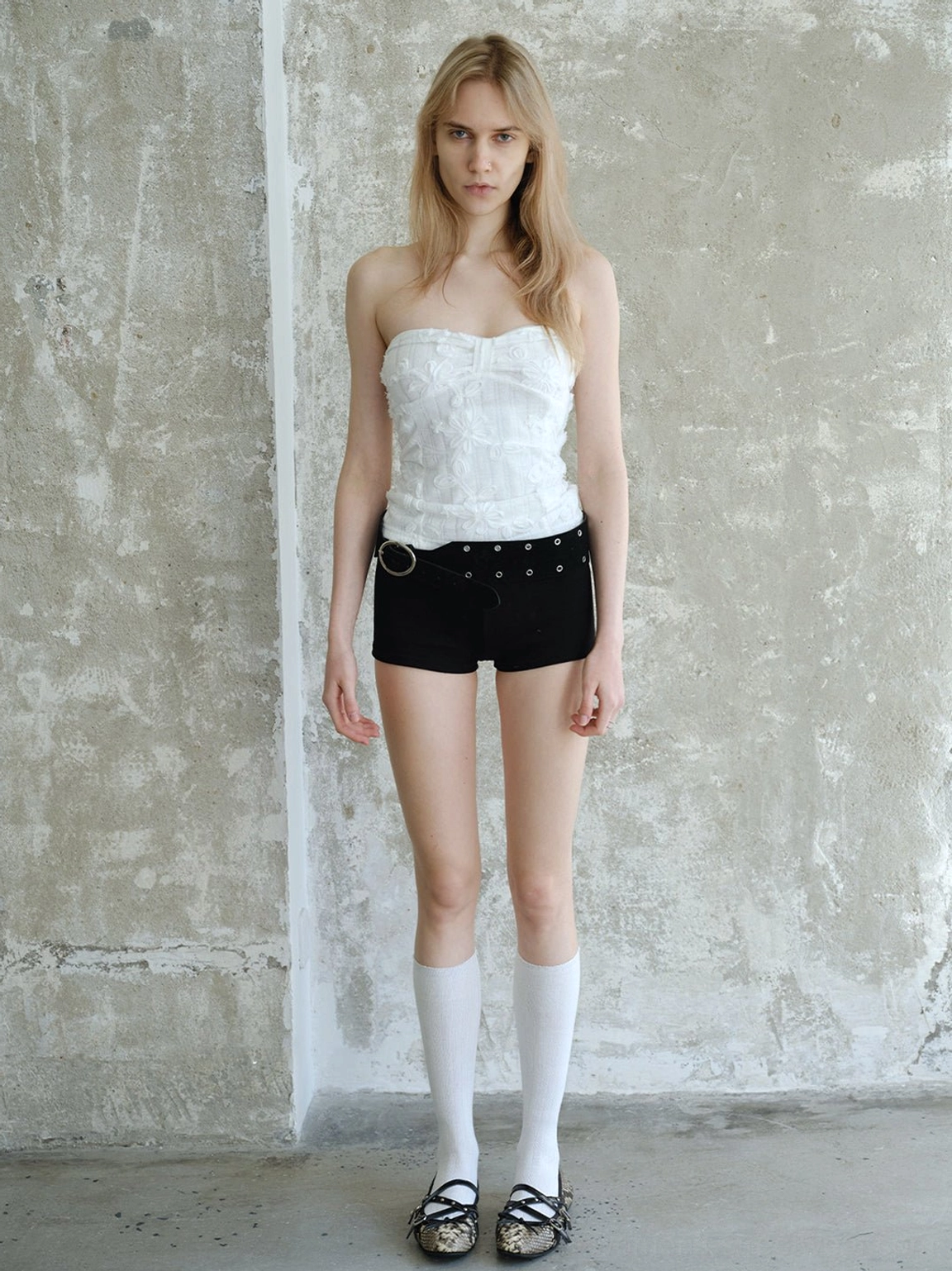 Snakeskin buckle ballet flats styled with white knee-high socks black shorts and white strapless top