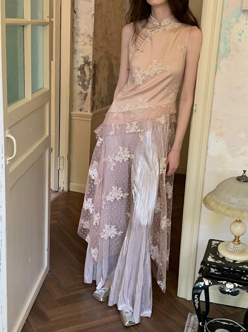 Full-body side view of a soft blush embroidered cheongsam-inspired wide-leg jumpsuit with floral mesh overlay and elegant silver pointed-toe heels