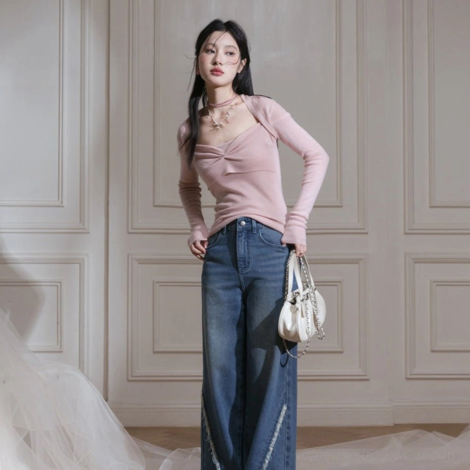 Full body view of soft blush pink twist front knit top with fitted sleeves and wide leg blue jeans