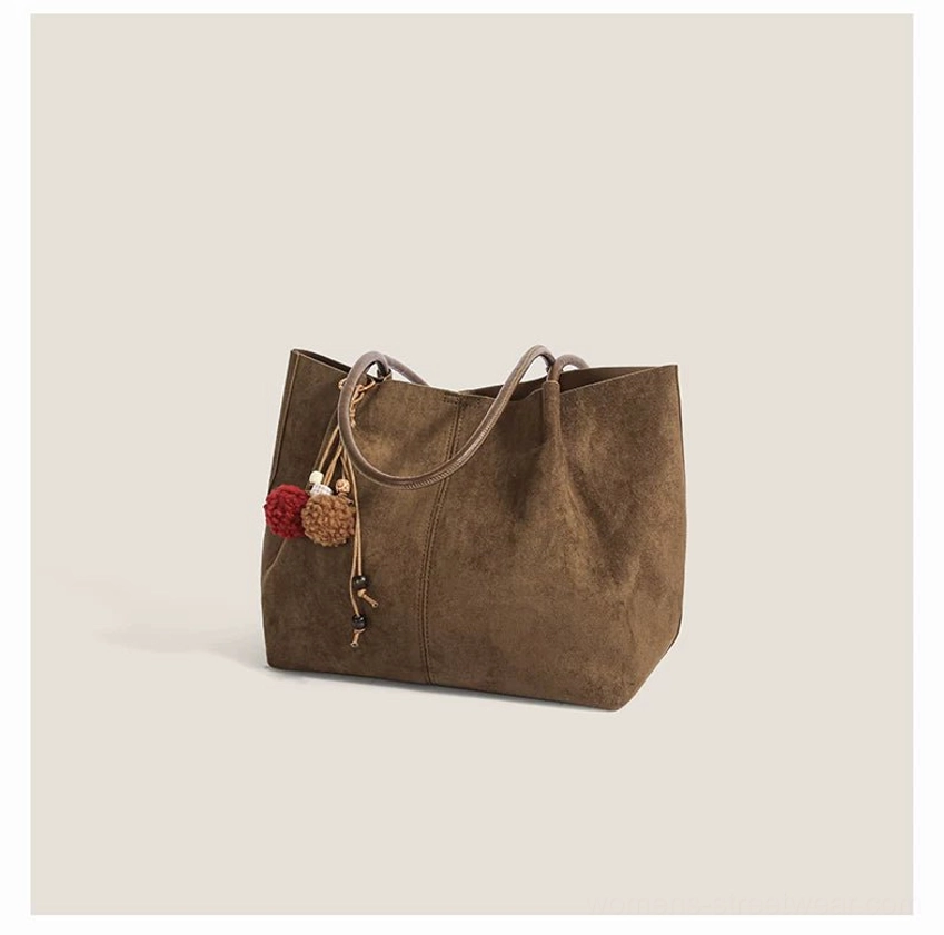 Soft faux suede Korean streetwear tote bag with decorative pom pom tassel charm and spacious everyday carry silhouette
