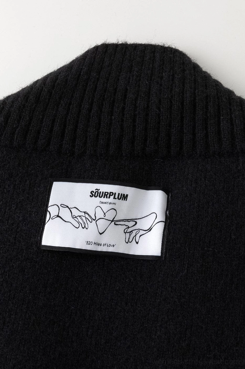 Close up back collar detail of solid black knit V-neck racing stripe sweater showing ribbed texture