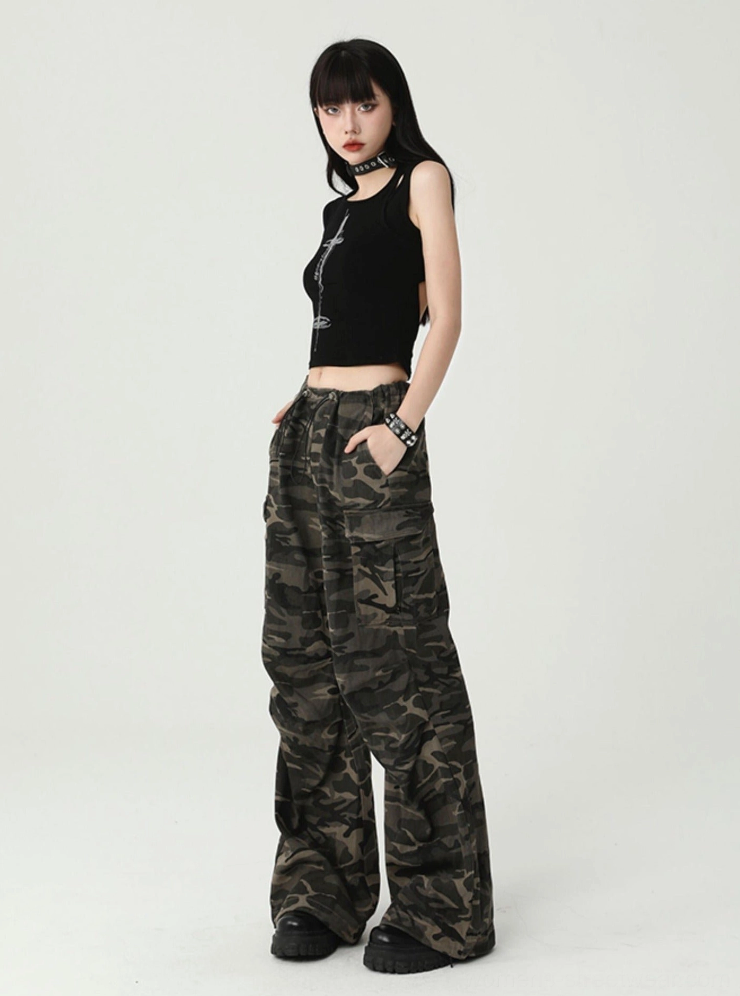 Side view of a solid black cropped tank top with ribbed knit texture, sleeveless cutout design, fitted shape, and gothic streetwear attitude