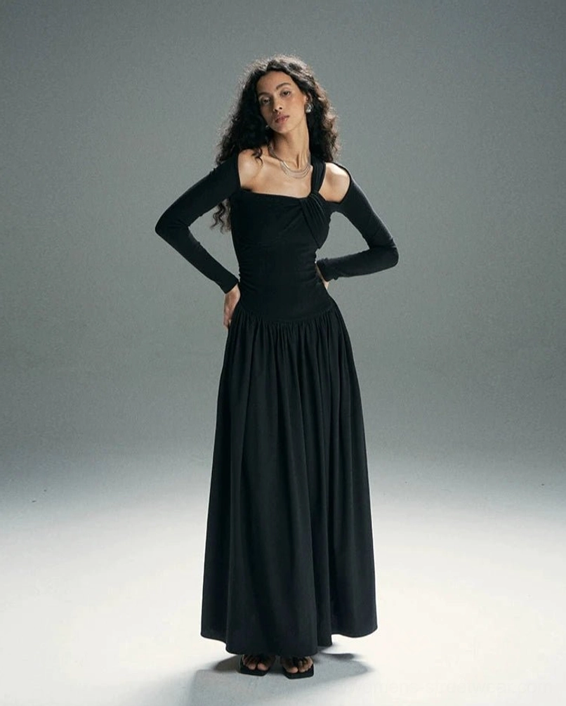 Solid black asymmetrical twist cold-shoulder maxi dress with fitted bodice and full gathered floor-length skirt shown in a studio fashion view