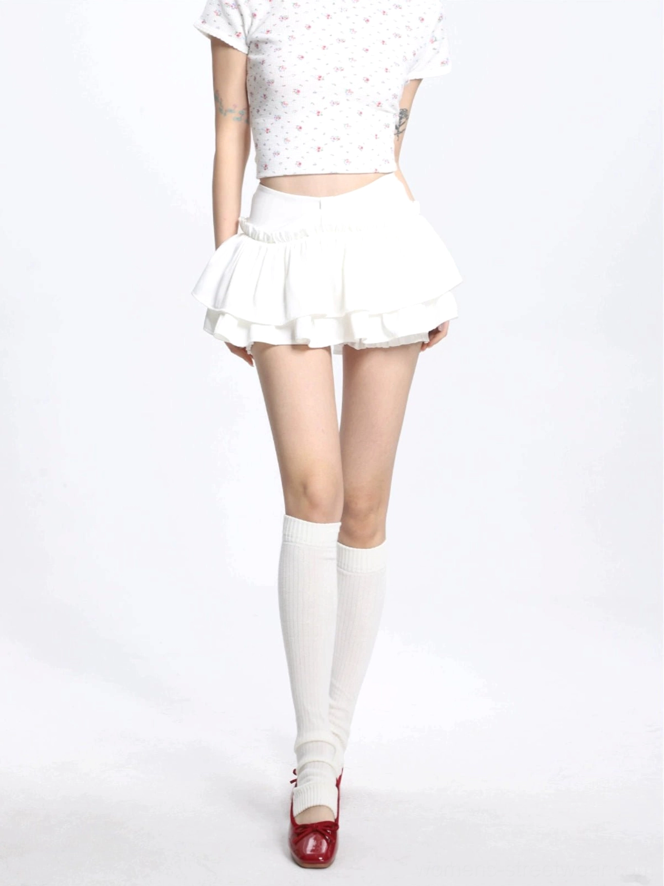 Back three quarter view of a solid white high waisted mini skirt with a flowing double ruffle hem for feminine streetwear styling