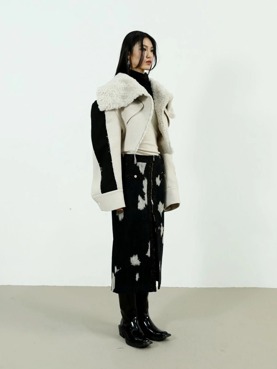 Side profile of women's speckled corduroy midi skirt styled with a matching shearling coat and black leather boots