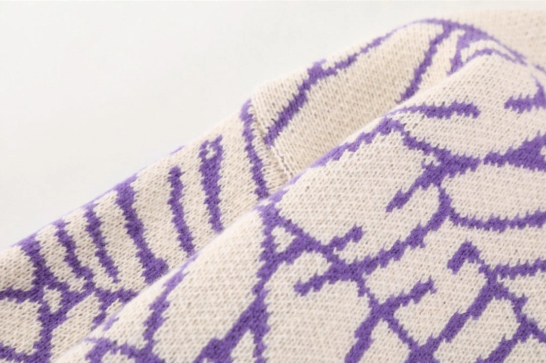 Detailed close-up of chunky purple spider web jacquard knit sweater fabric and shoulder