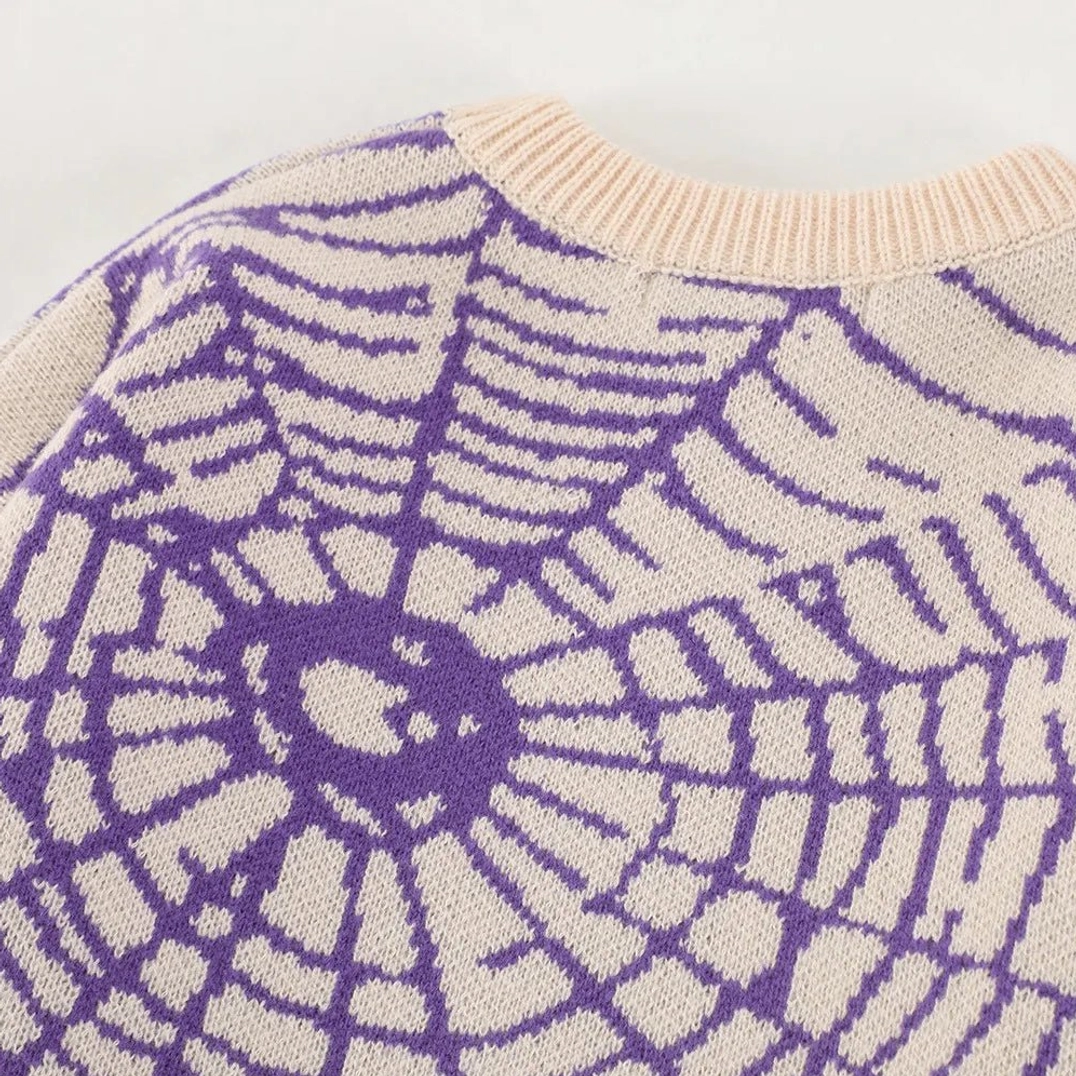 Close-up of purple spider web jacquard knit sweater shoulder and ribbed crewneck texture