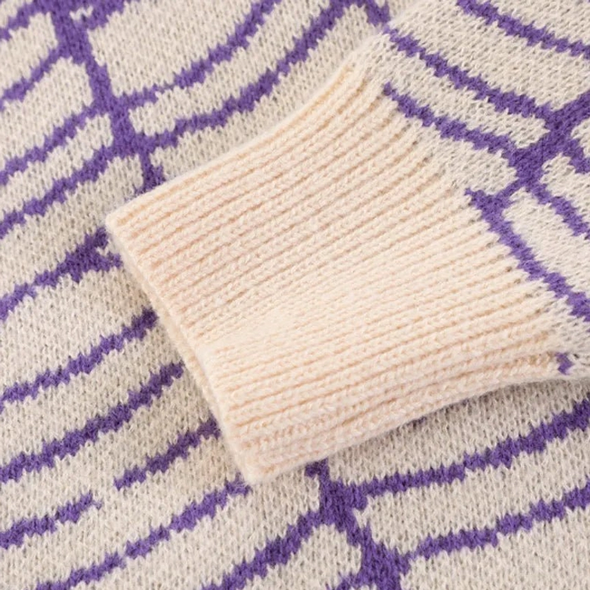 Close-up side view of purple cream spider web knit sweater ribbed cuff and knit pattern