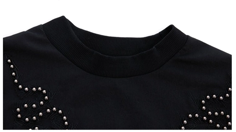 Close-up of the black studded fitted T-shirt showing the ribbed crew neck and swirling chest and shoulder details