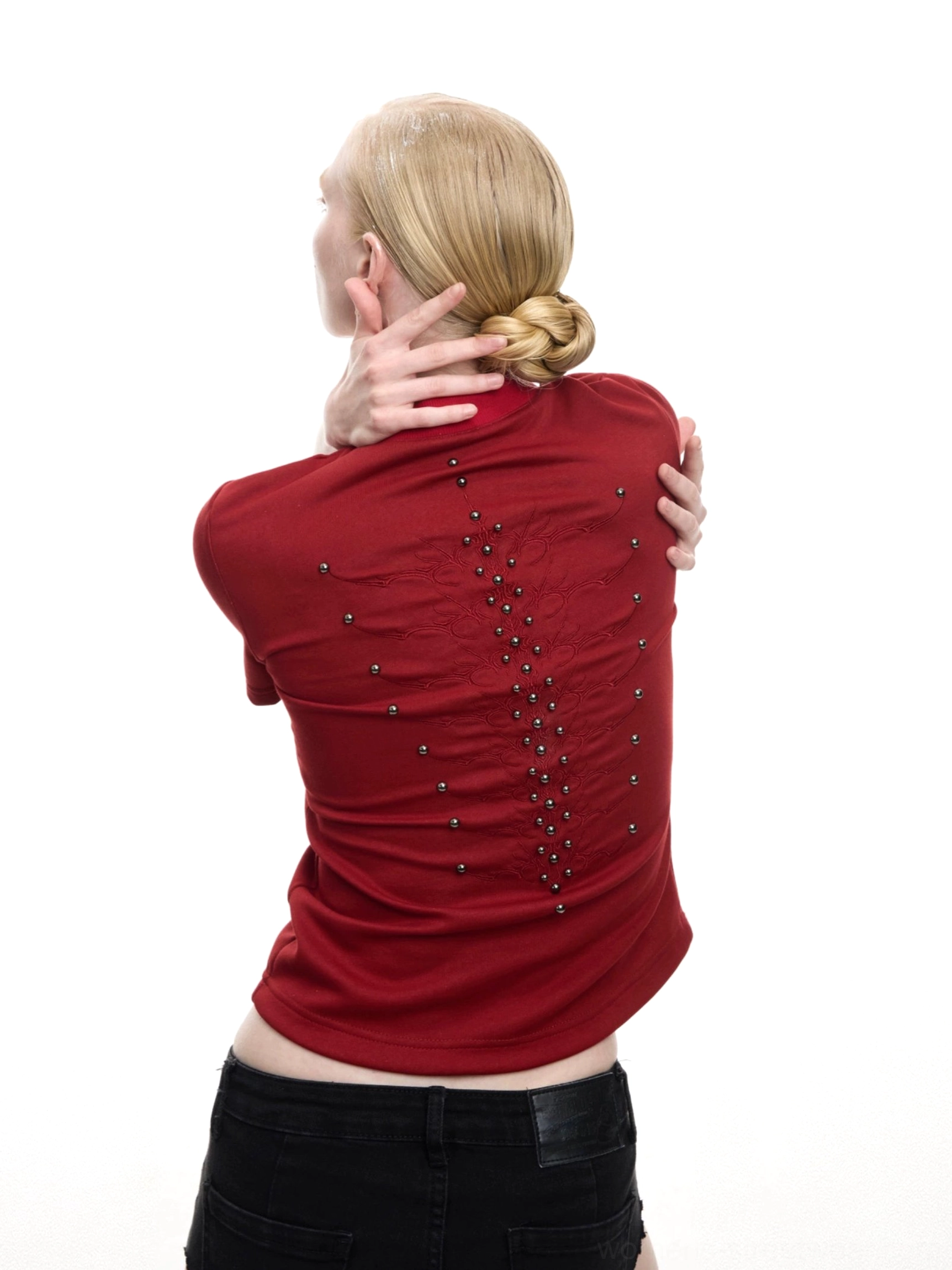 Burgundy red fitted studded T-shirt shown from a rear three-quarter angle with a spine-inspired crystal embellishment