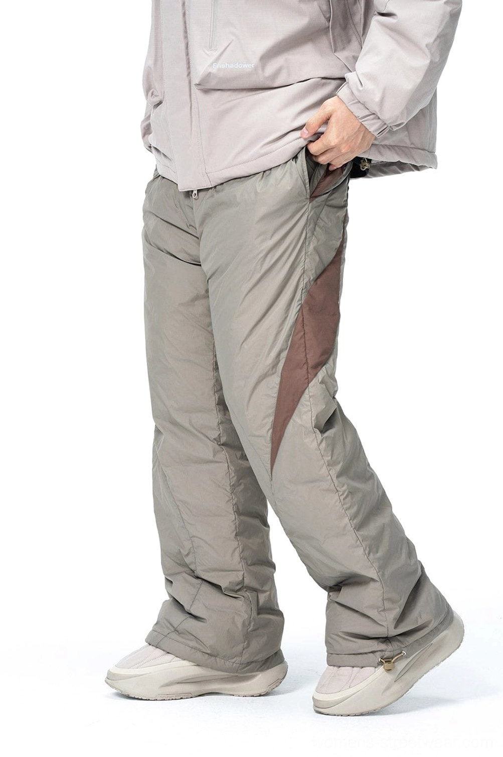 Front side view of spliced padded streetwear pants showing the side waist pocket curved brown panel and quilted texture