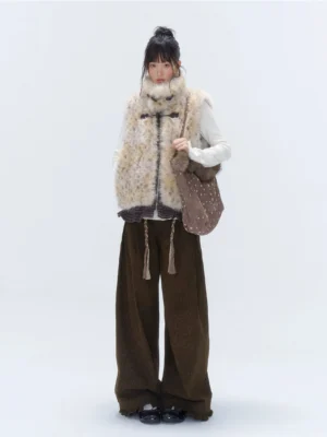 Model carrying brown deer spot faux fur trim tote bag on shoulder with faux fur vest and wide leg pants