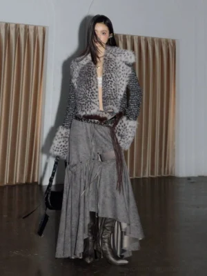 Front view of a grey spotted faux fur cropped tweed jacket styled with a maxi skirt, leather boots, waist belt, and black shoulder bag