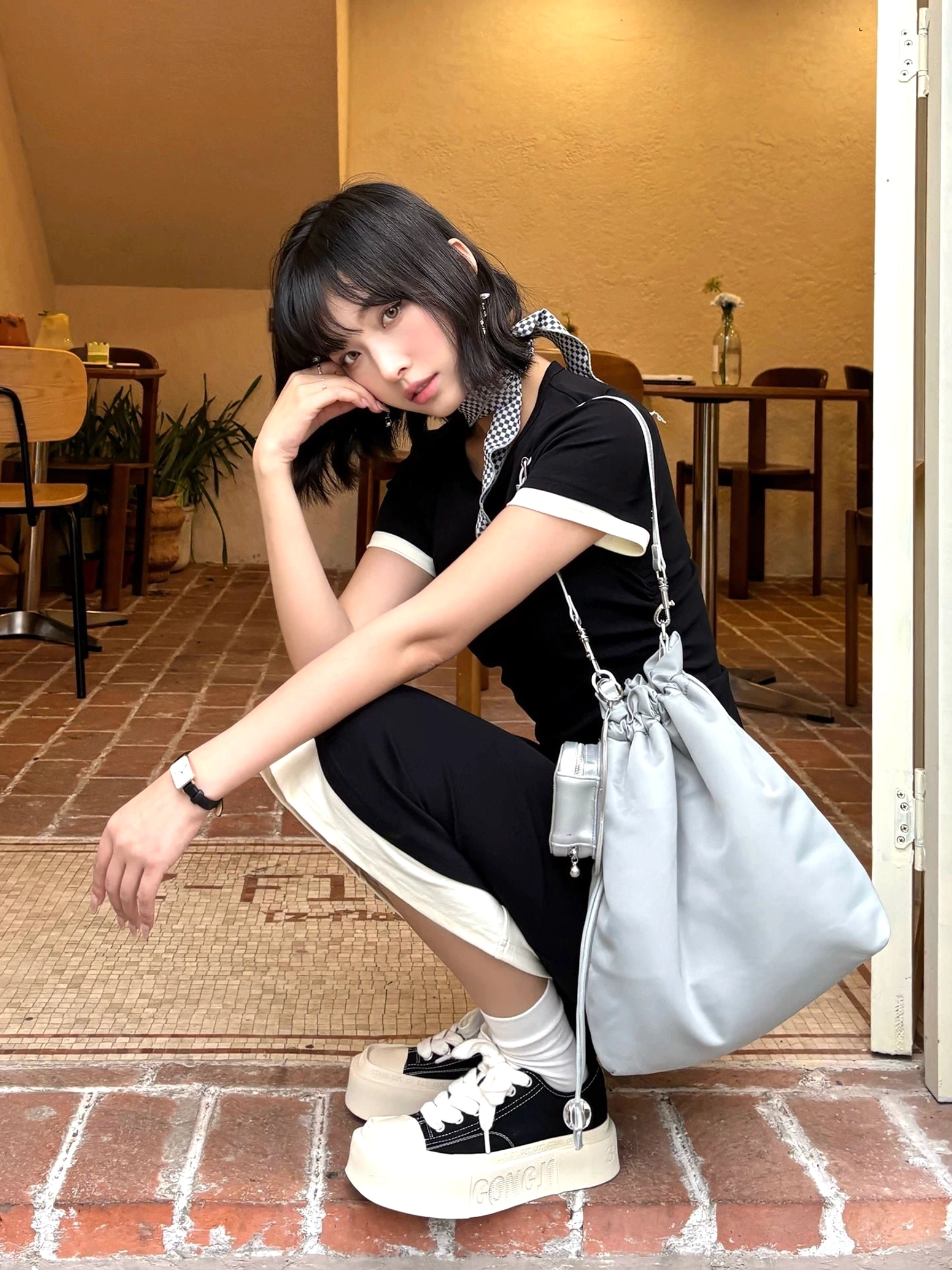 Black and white square toe platform canvas sneakers with thick rubber sole styled at a retro restaurant entrance