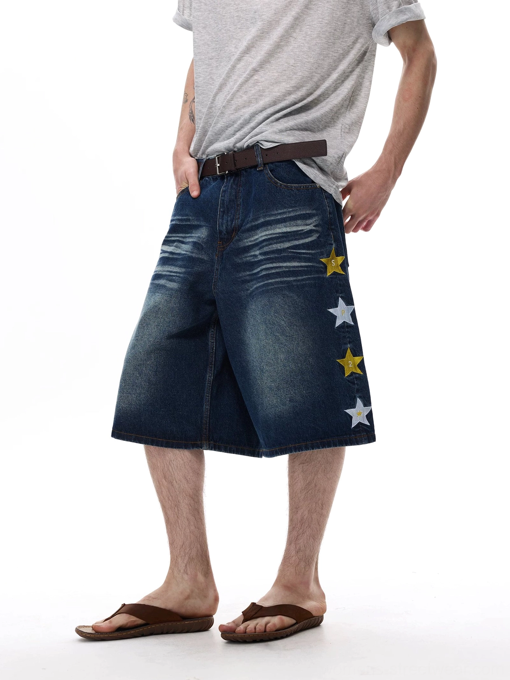 Close-up front view of dark blue star appliqué wide-leg denim knee shorts with belt loops and faded wash
